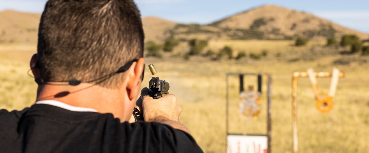 shooter aiming a handgun at a couple targets outside