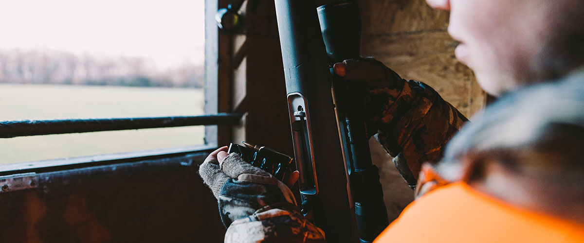 hunter loading a rifle in a blind