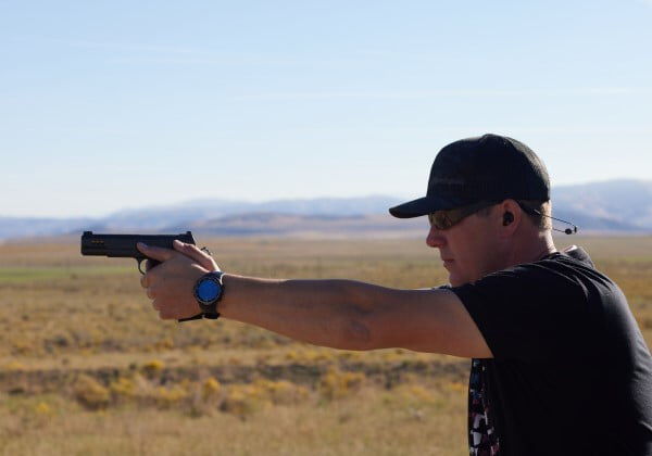 person aiming a handgun outside