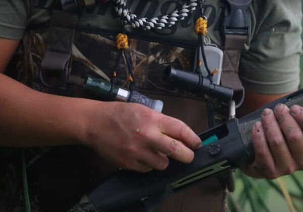 hunter loading a shotshell into their shotgun