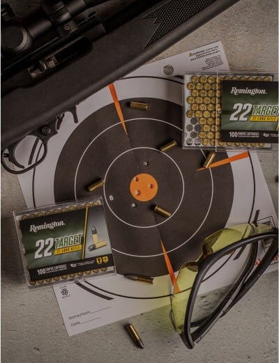shot target, 22 target packaging, spent cases, rifle, and eye protection on a table