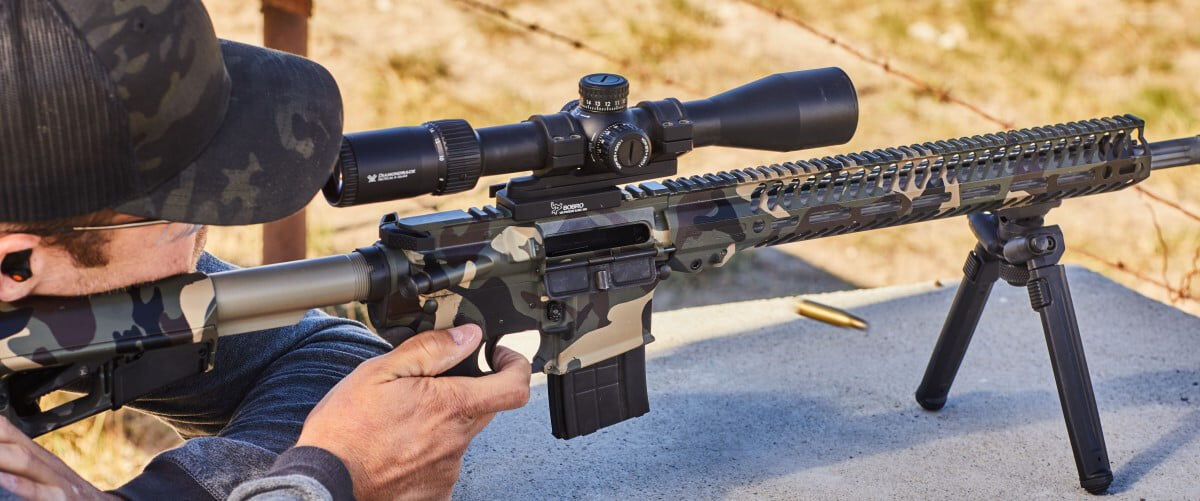 shooter looking down the scope of a rifle balanced on a table