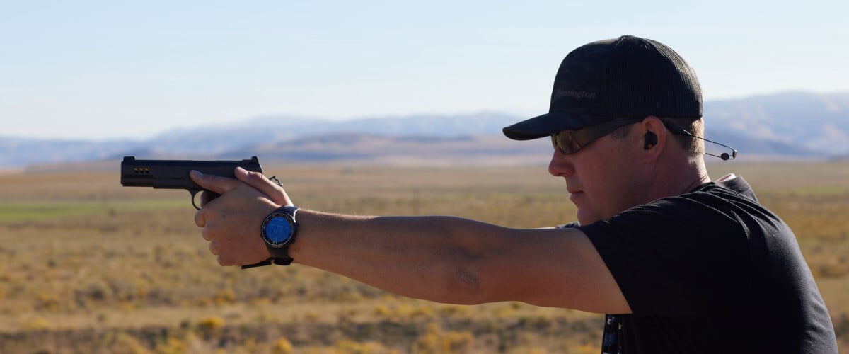 person aiming a handgun outside