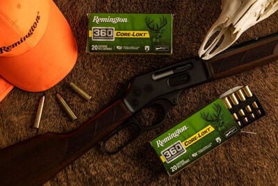 lever action rifle laying on a table with a box of Core-Lokt 360 Buckhammer, cartridges, skull, and orange hat