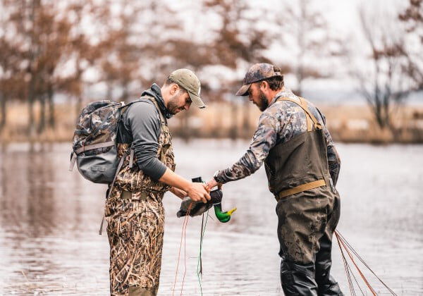 two hunters standing in water with duck decoys