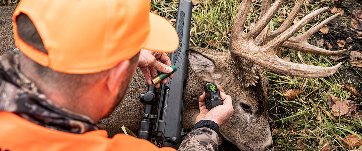 hunting kneeling over deer with shotgun and slug