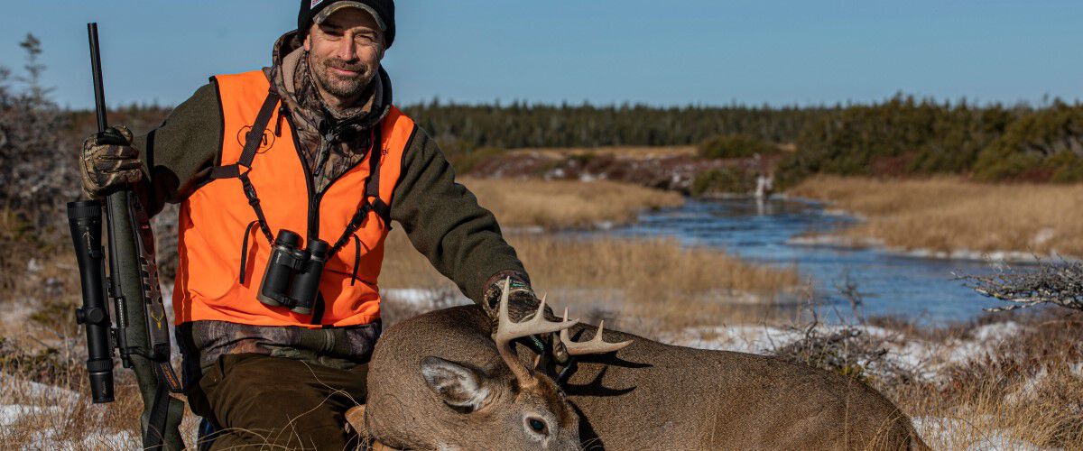 hunter kneeling beside a dead deer