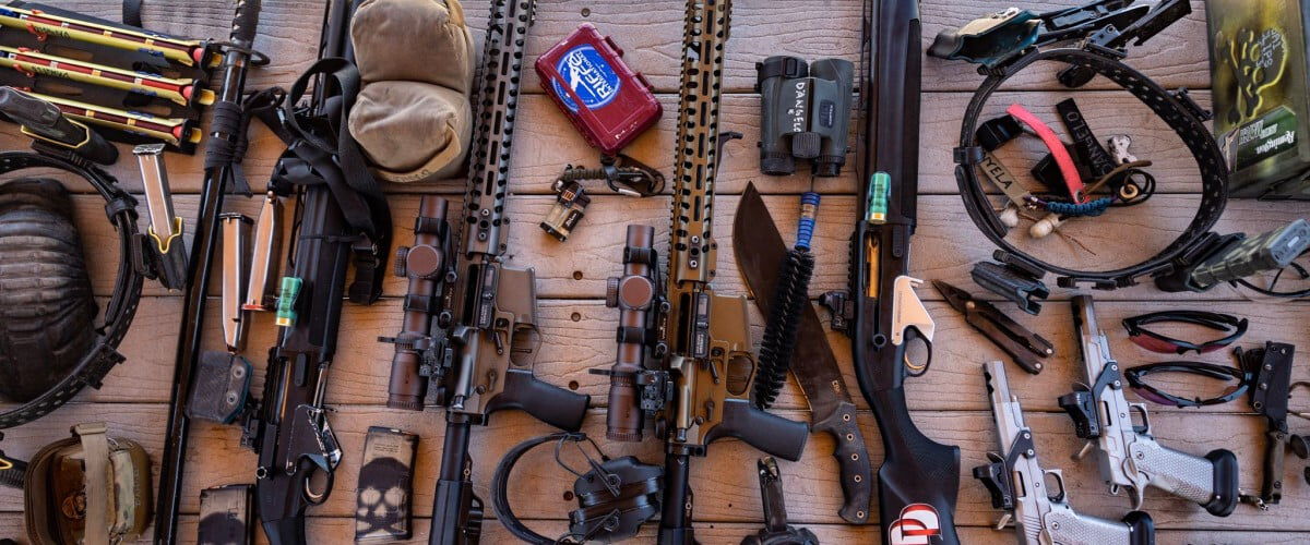 guns, ammo, and accessories laying on a table