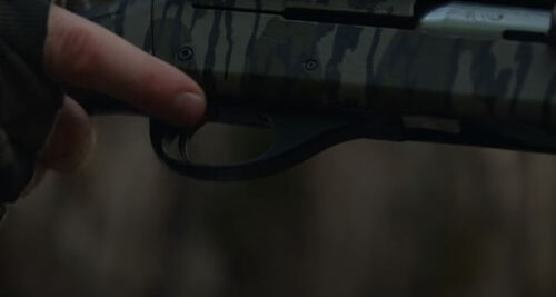hunter with their finger by the trigger of a shotgun