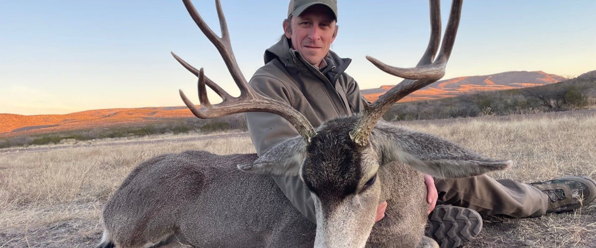 hunter sitting behind dead deer