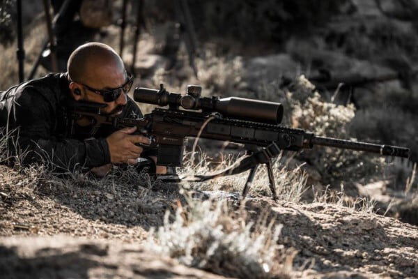 Dustin Sanchez looking down the scope of a rifle