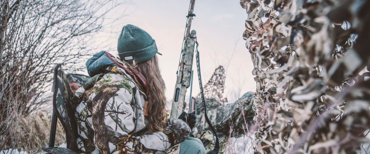 Hunter sitting in a blind holding a shotgun