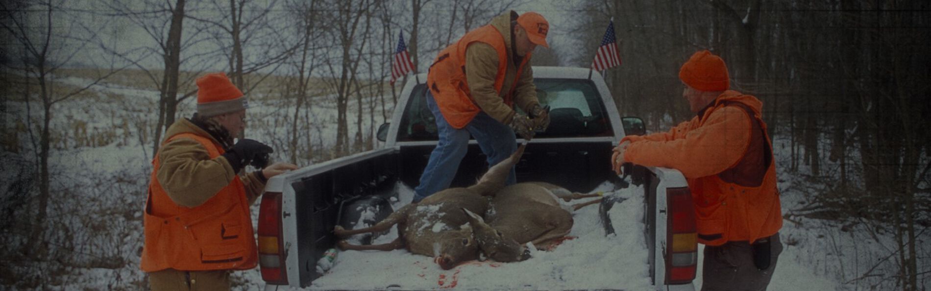 men loading a dead deer into a pick up truck bed