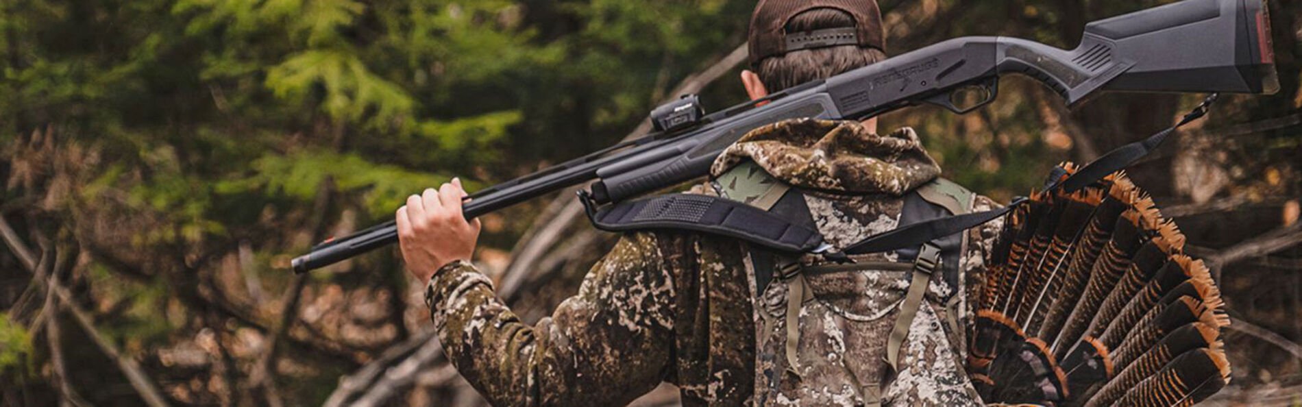 hunter walking with a turkey and his shotgun on his back