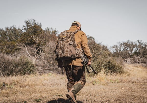 hunter walking away from while carying a rifle