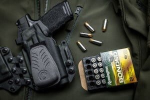 Golden Saber Bonded box laying next to a handgun in a holster