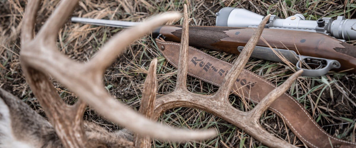 deer antlers and a rifle laying in the grass