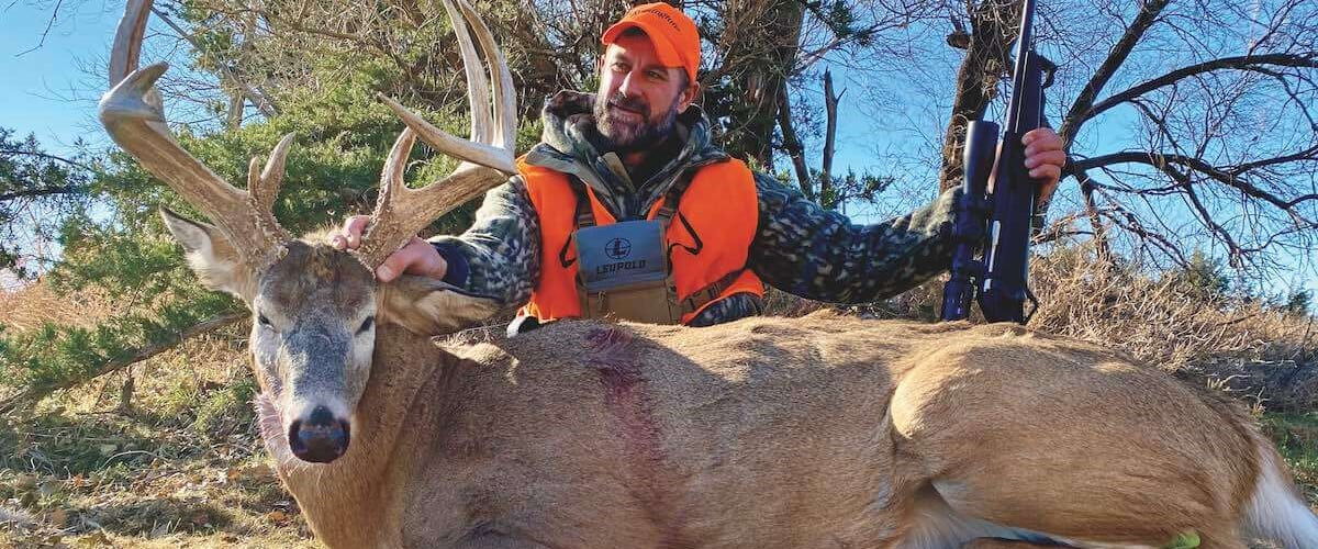 hunter kneeling beside a big buck