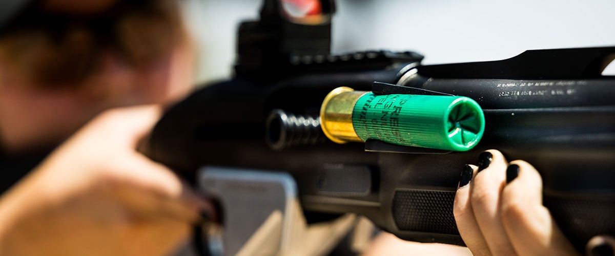 person aiming shotgun with Remington shotshell attached to the shotgun