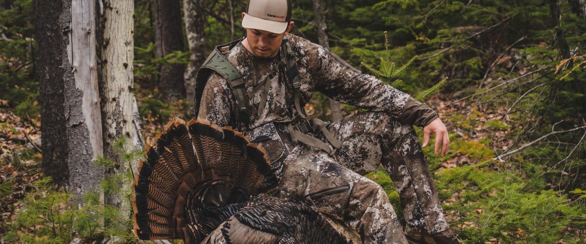 hunter holding up turkey tail in a wooded area