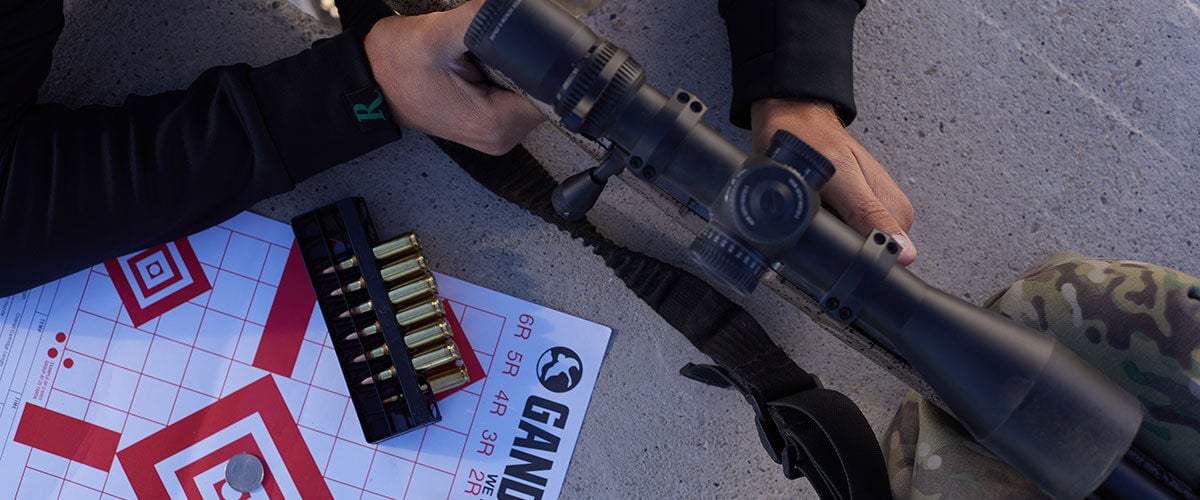 shooter holding rifle, Remington cartridges and a target