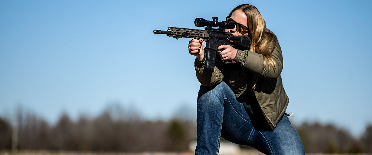 Shooter using knee as rest while aiming rifle