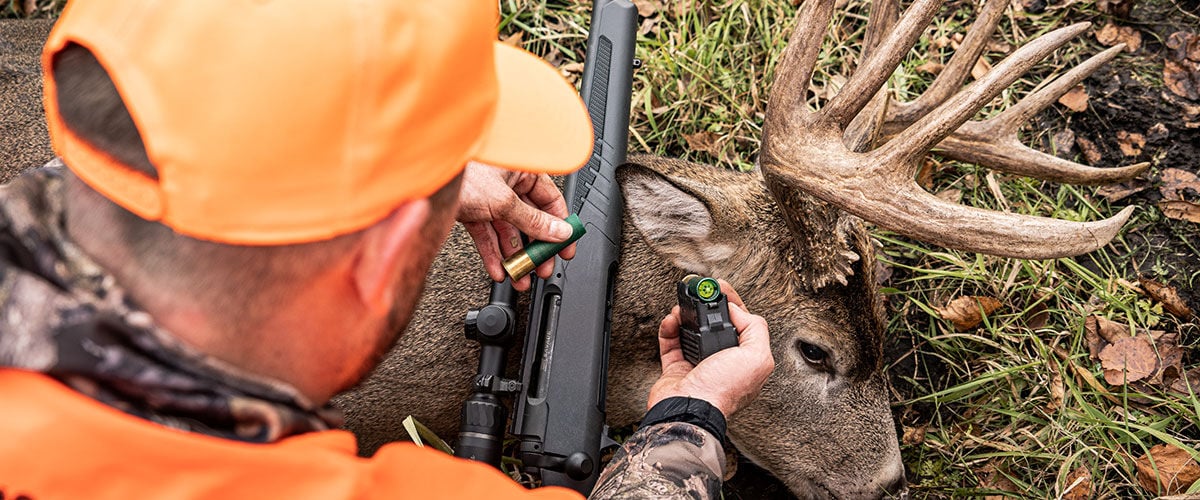 hunting kneeling over deer with shotgun and slug