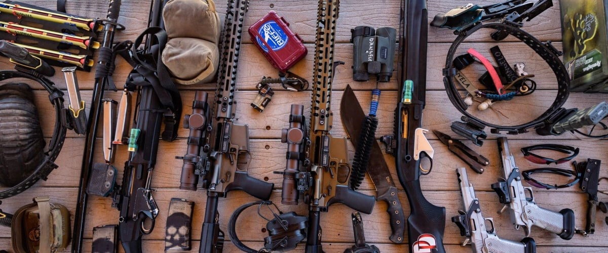 different guns and gear laying on a table