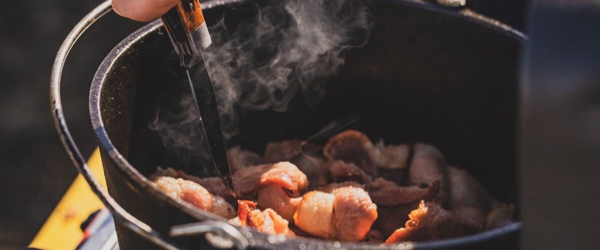 Remington knife being used to stir some meat in a cast iron pot