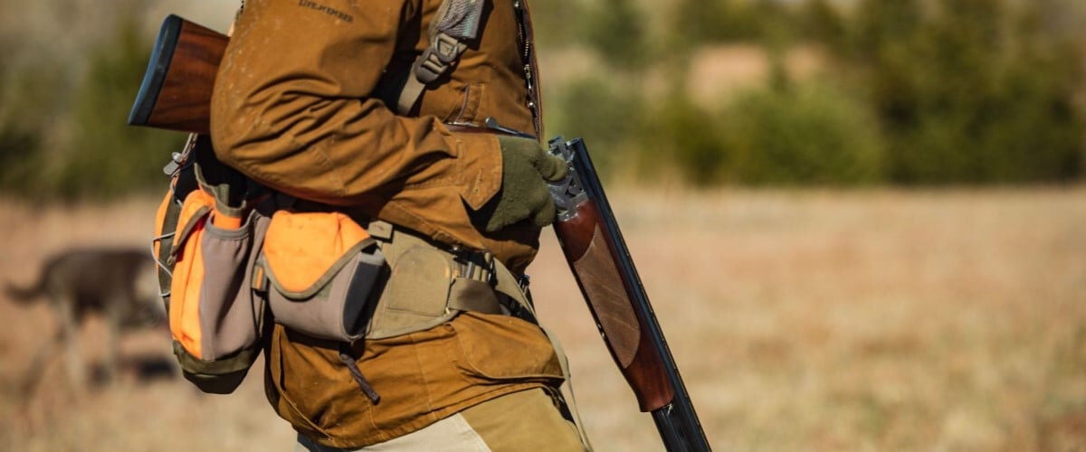 hunter walking with hunting vest and shotgun